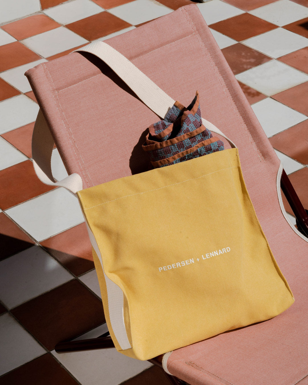 Yellow bag with 'PEDERSEN + LENNARD' text on a checkered floor
